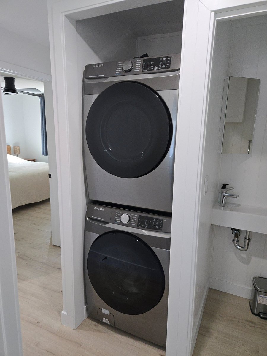 Stacked Samsung Washer and Dryer, both have steam cleaning functions. Located in the hallway.