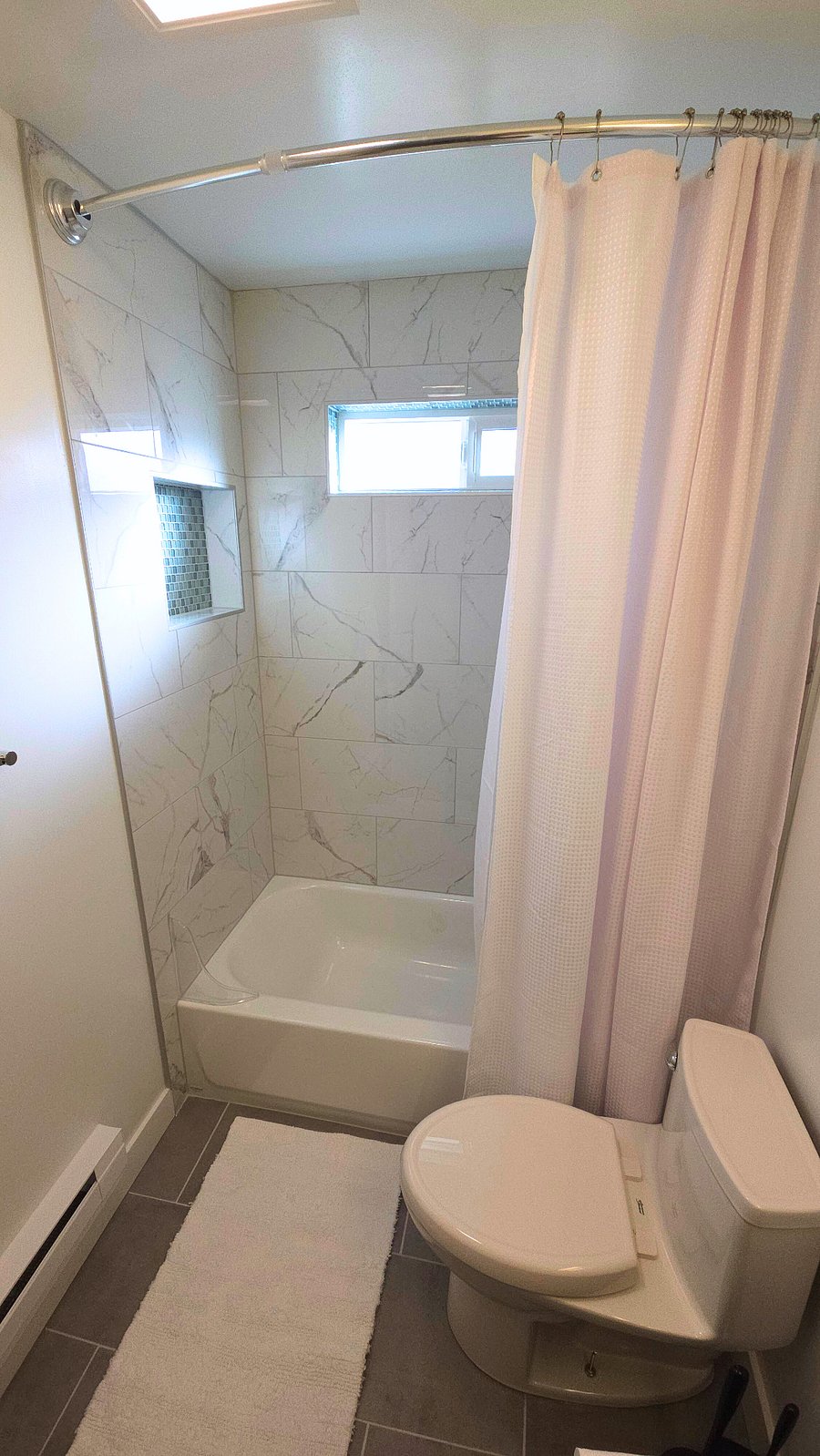 Full size soaking bathtub surrounded with luxury Statuario polished marble tile. Large shower niche for full size shampoo and soap bottles. Chrome Delta shower hardware with high pressure adjustable shower head. Curved shower curtain rod for more space while showering. Two piece shower curtain and liner (washed between tentants).