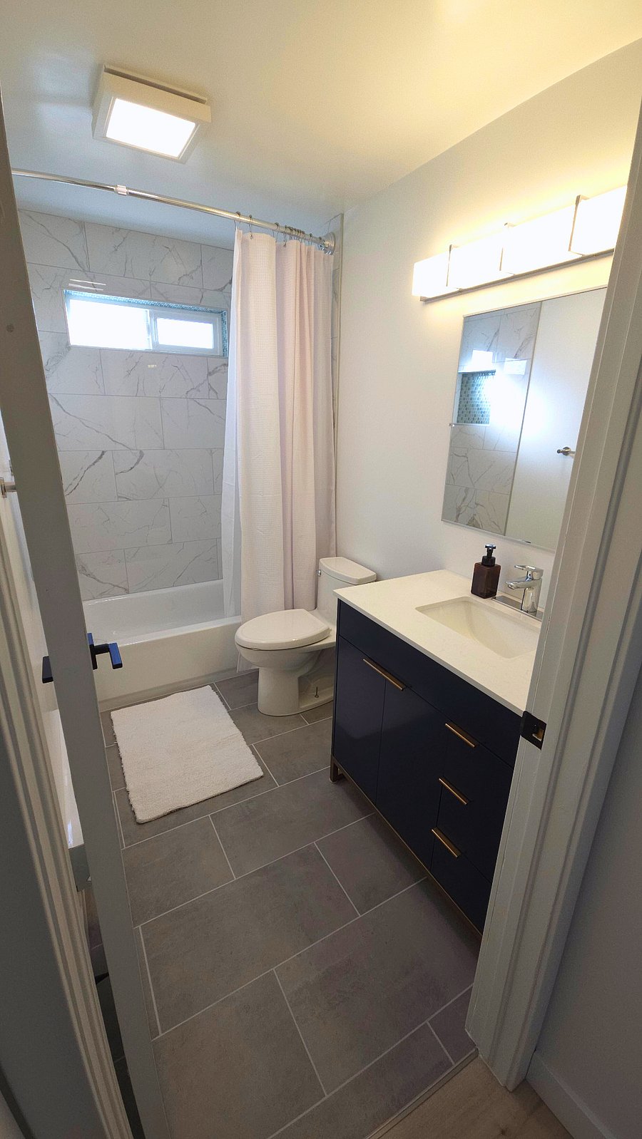 Main bathroom. High-end chrome fixtures. Full size soaking bathtub surrounded with luxury marble tile. Full size one piece, seat height, elongated bowl toilet. Italian made porcelain floor tile with matte finish.
