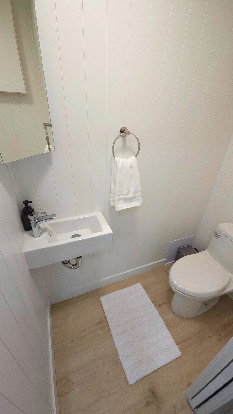 Nice porcelain sink, Hansgrohe single lever faucet. One piece American Standard seat height toilet with elongated bowl. Stainless steel trash can, toilet brush and plunger. Bathroom exhaust fan.