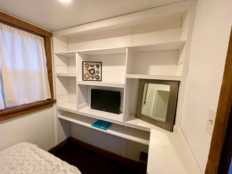 Downstairs bedroom. Twin XL bed with bookshelf nook, and built in wall of shelves with a desk.