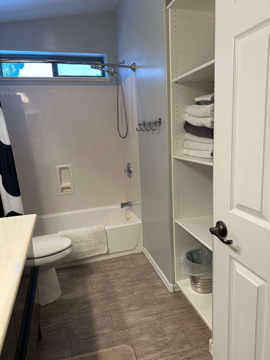 Large full bathroom with shelves, closet and drawers for storage.