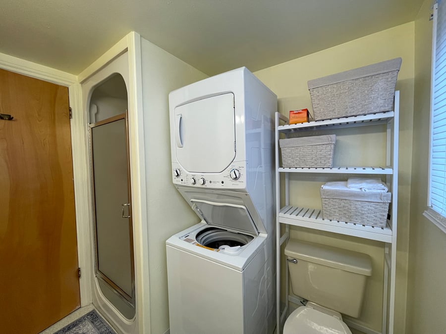 Shower, stacked washer dryer, bath storage.