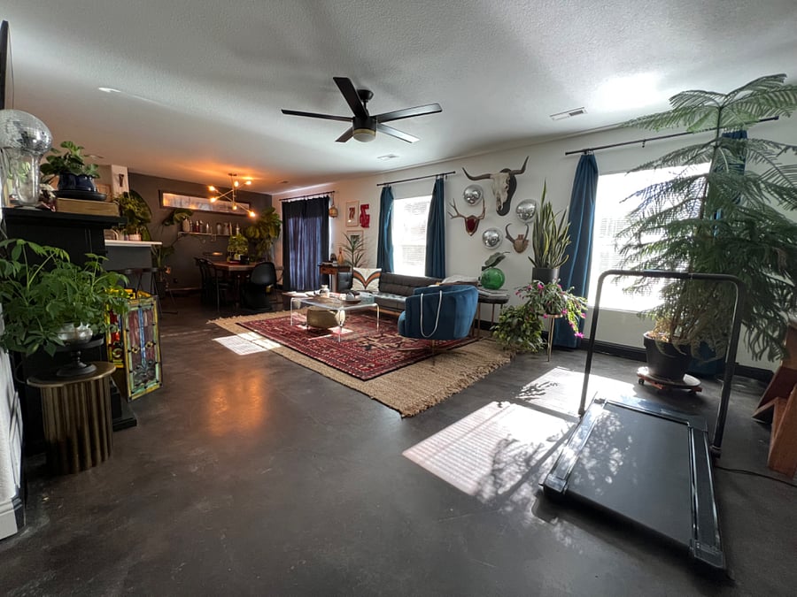 Spacious shared living/dining area with satellite TV, fireplace, exercise equipment, dining table, large windows and views into the backyard.