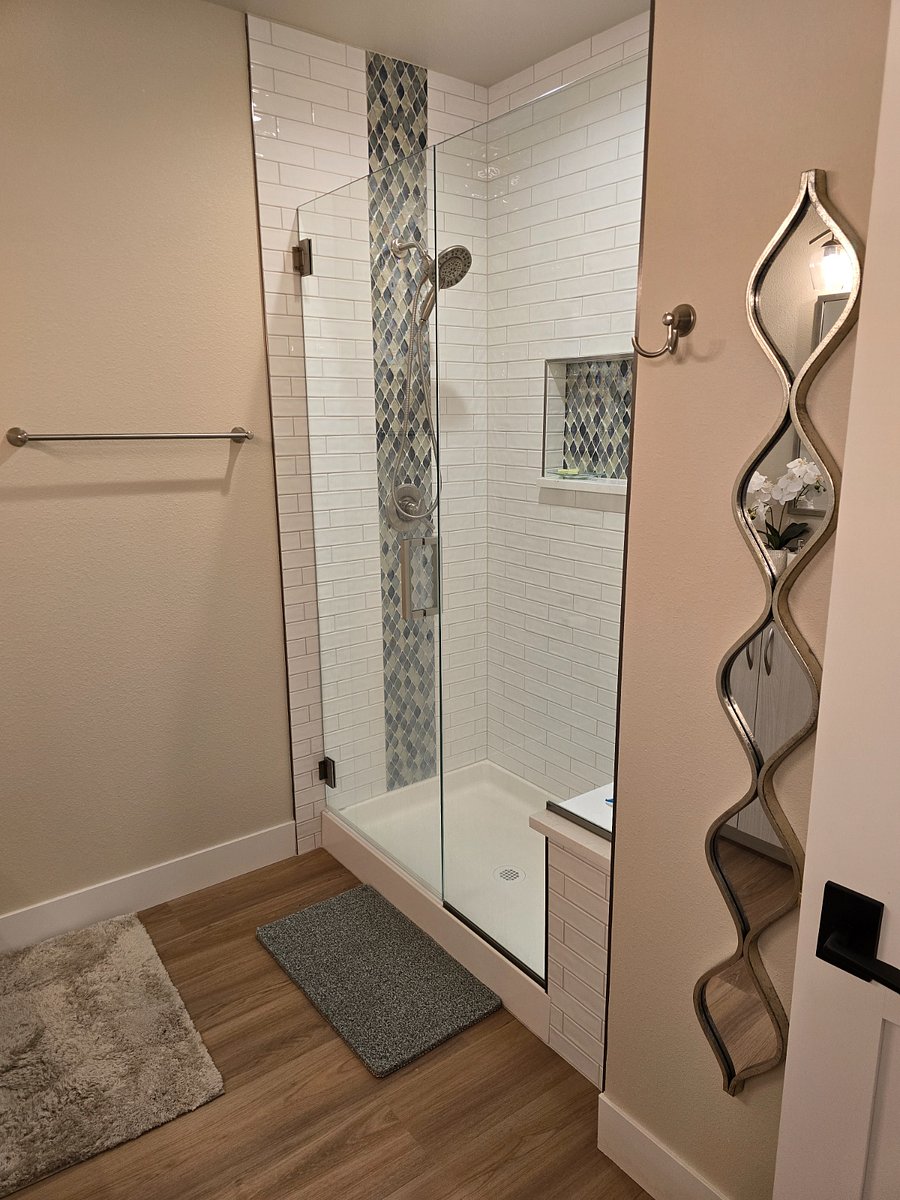 Master shower with built-in seat and custom tile with hand held shower head.