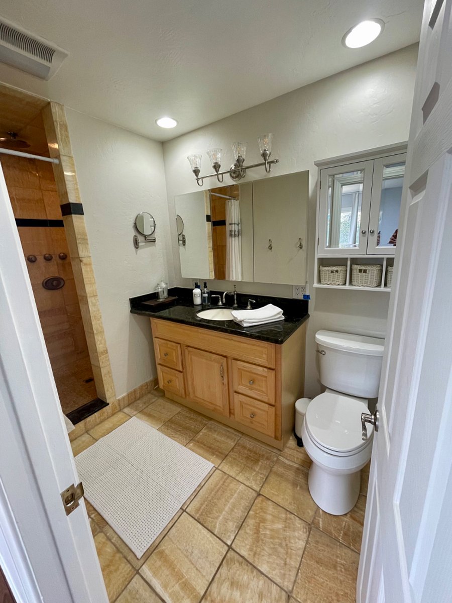 A beautiful bathroom with and extra large shower displaying a honey onyx surround and floor, as well as two shower heads.