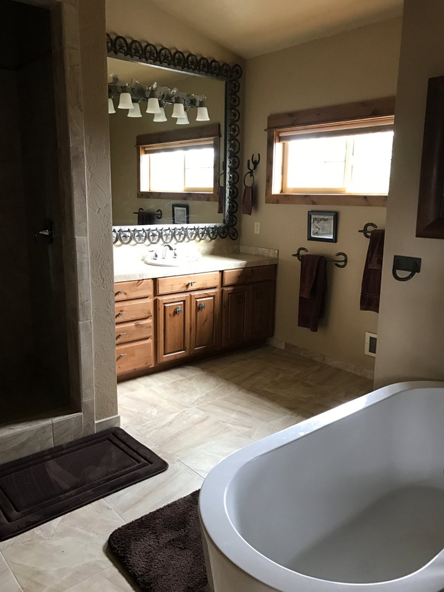 Large bathroom with separate bathtub and shower. The mirror is surrounded by a special frame made out of horseshoes.