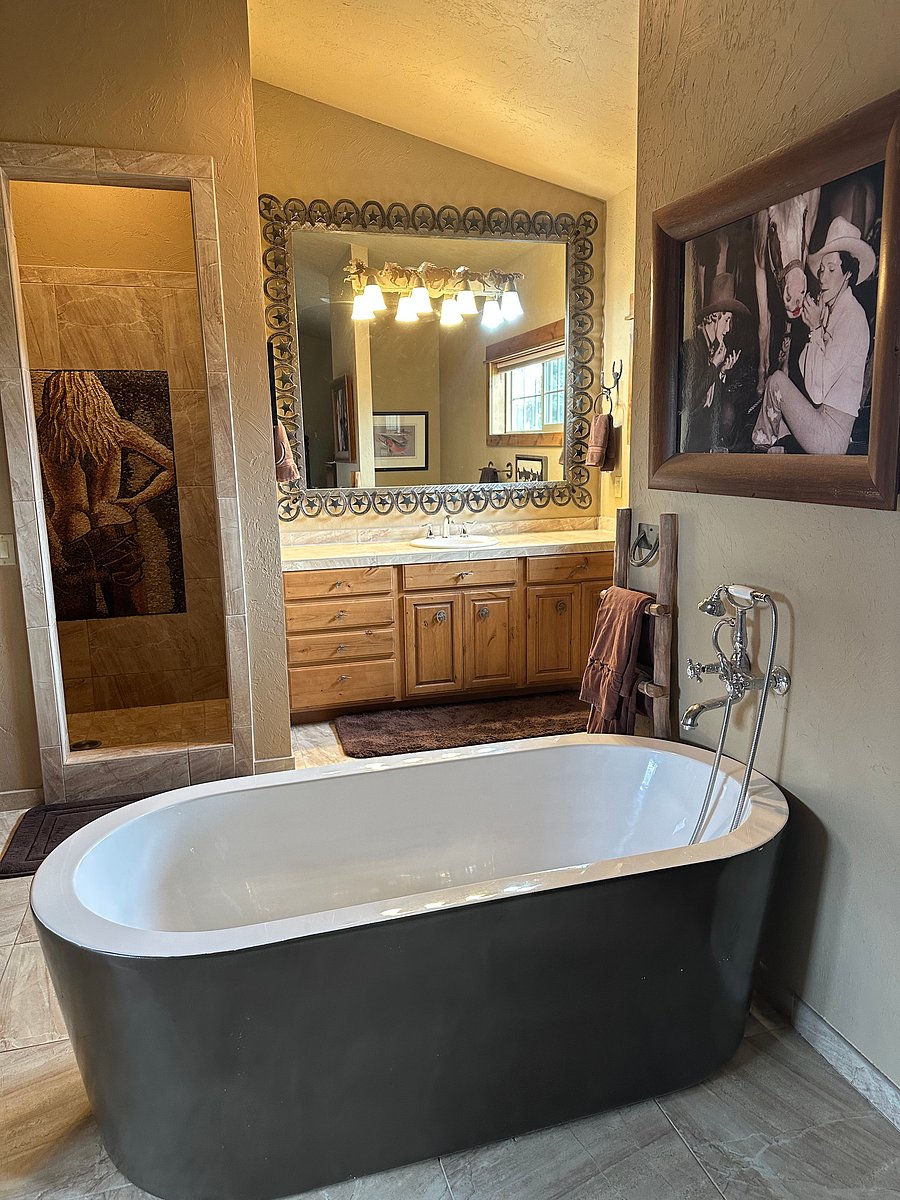 Bathroom off of the bedroom area that shows the separate bathtub and walk-in shower fully tiled