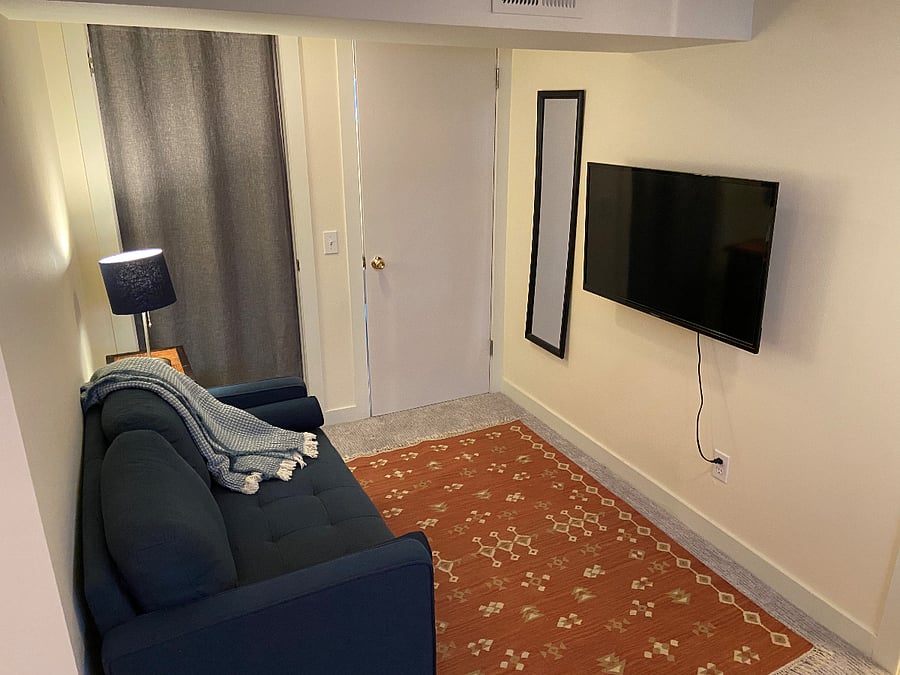 Loveseat and smart TV with curtained large closet door & door to livingroom