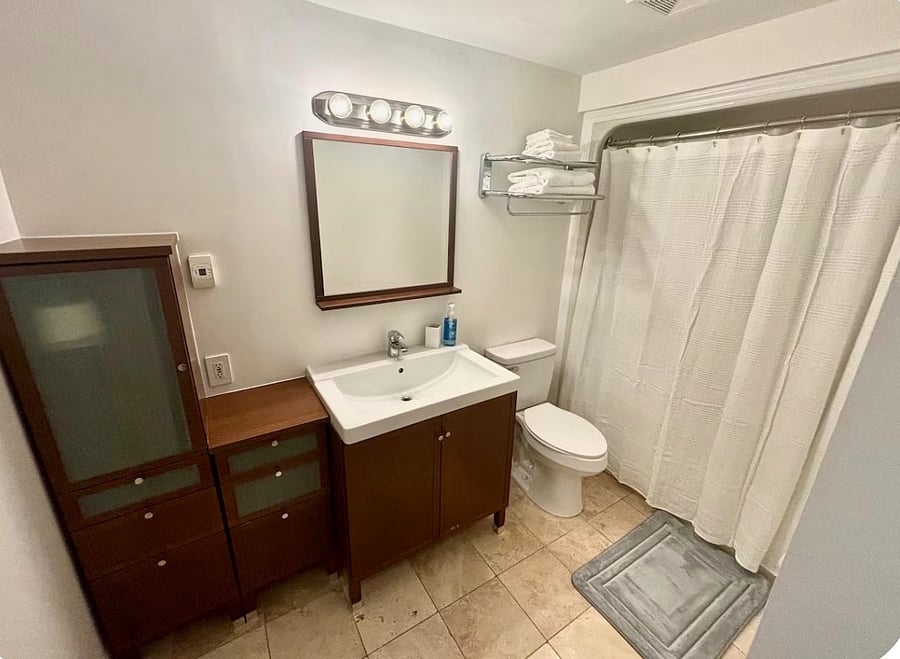 en-suite bathroom, adjacent to kitchen. also has condo's stacked washer dryer unit behind the door