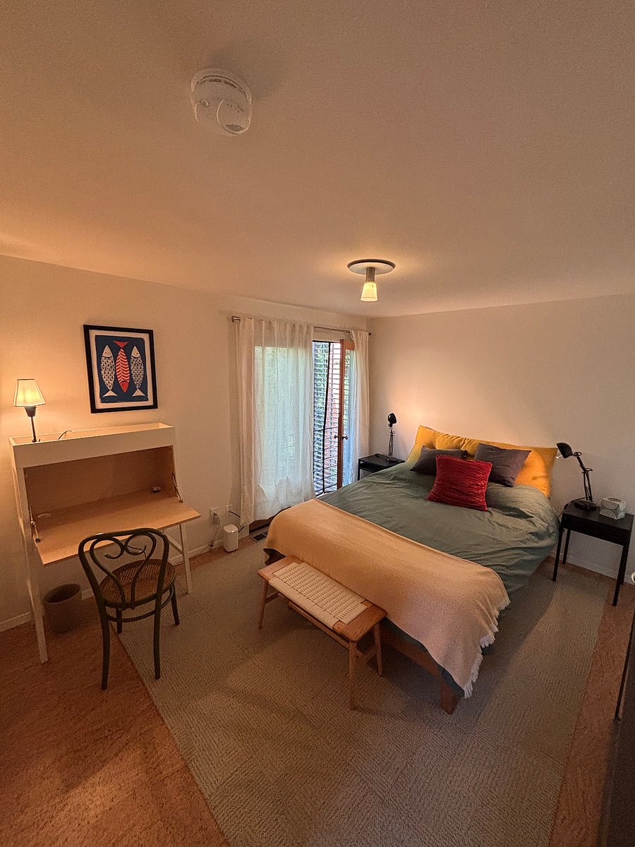 Primary bedroom with secretary desk, Juliet balcony, walk in closet and double doors (screened) to shaded quiet garden.