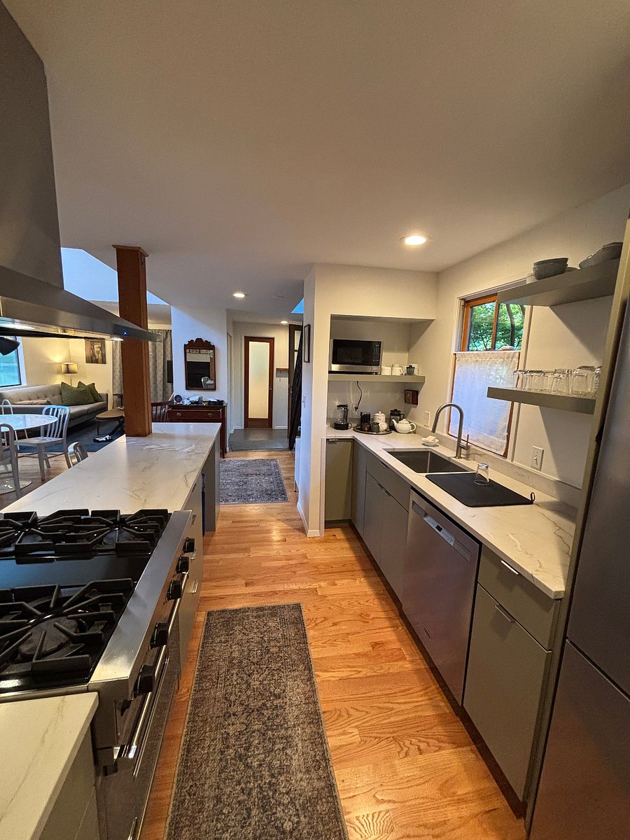 Kitchen view toward half bath and tiled entry foyer. Coffee/tea & microwave built in nook. Baking, cooking, glassware, dining amenities provided.