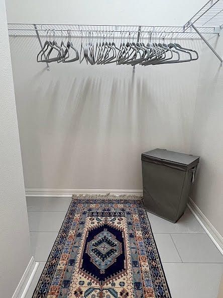 Spacious walk-in closet with plenty of storage space, hangars and a laundry hamper.