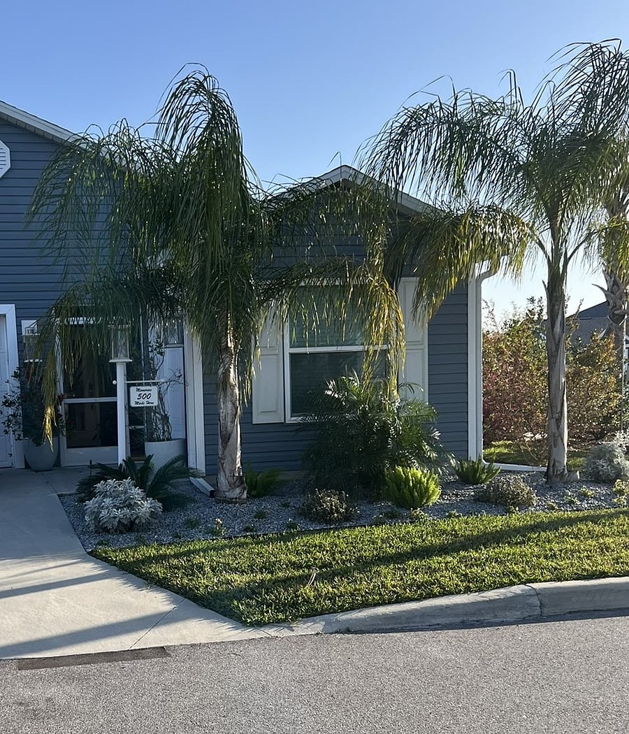 Front yard is professionally landscaped with palms native to Florida.