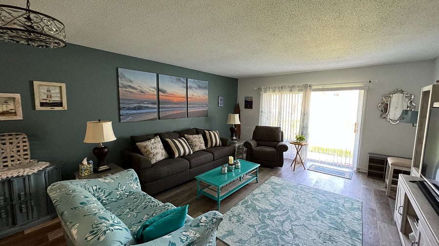 Open living area w/ TV, sound bar, sleeper sofa, recliner, and access to porch & pool