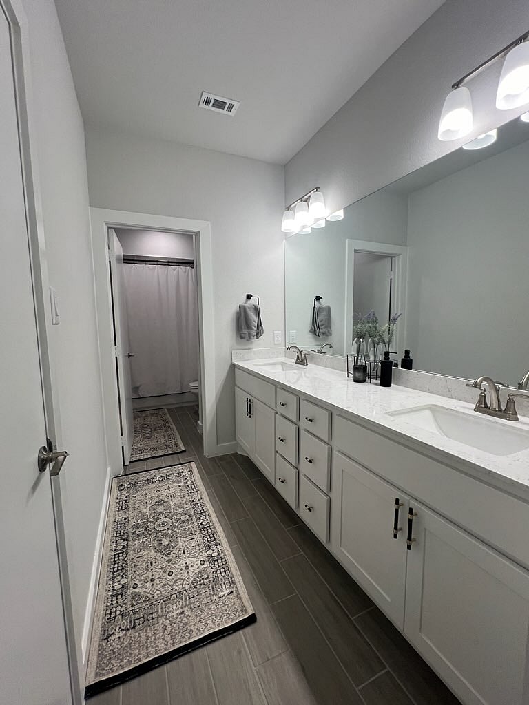 Second bedroom connected bathroom. Dual vanity sink and large mirror. Shower with tub