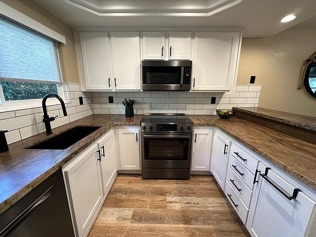 Kitchen with ample storage, oversized sink, granite counters, black stainless Bosch appliances: electric range/oven, dishwasher, microwave, refrigerator.