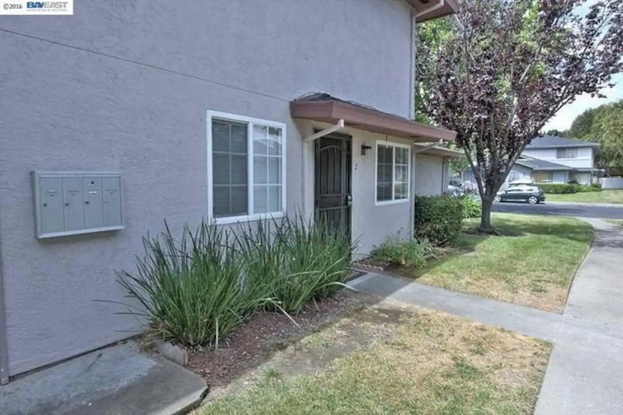 A view of the exterior door and mailbox as well as street parking.