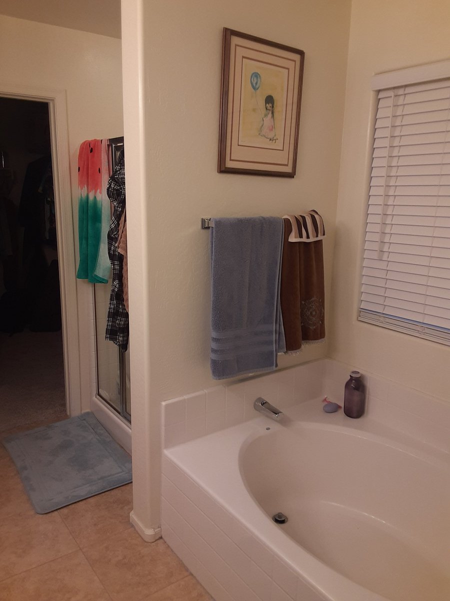 tub with separate shower and door to walk in closet