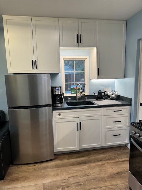 Kitchen with full-size refrigerator, sink, oven, stove, microwave, RO water filtration system and plenty of shelves and kitchen essentials.