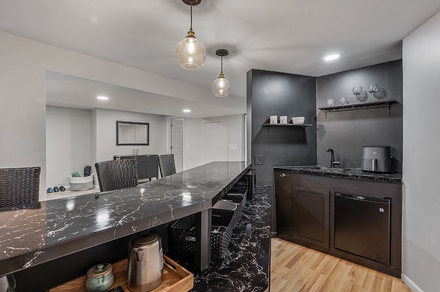 Wet bar has small refrigerator, microwave, air fryer, toaster, tea kettle, coffee maker, dishes, utensils, and other miscellaneous kitchen supplies.