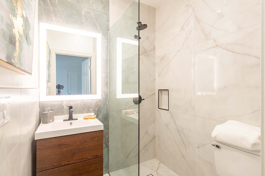 Ensuite private bathroom with large backlit mirror, porcelain surround