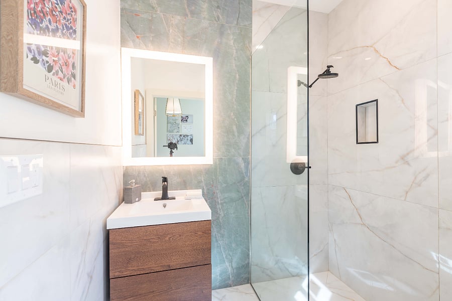 Ensuite private bathroom with large backlit mirror, porcelain surround