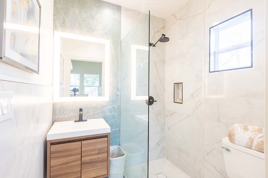 Ensuite private bathroom with large backlit mirror, porcelain surround