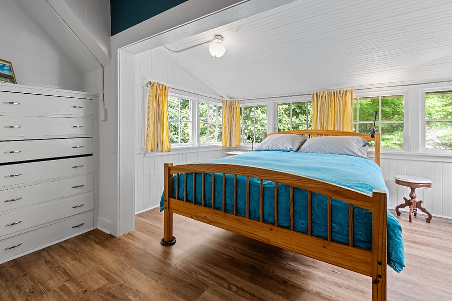 Large bedroom with sunny windows in the tree tops