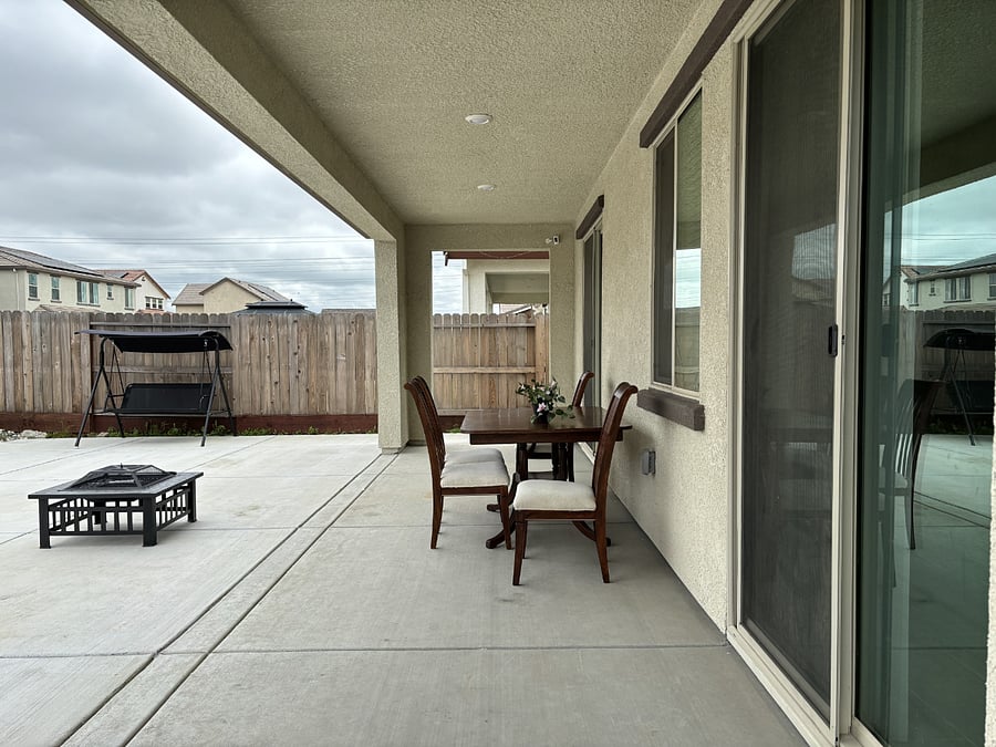 Backyard with dining table, firepit, and many fruit trees.