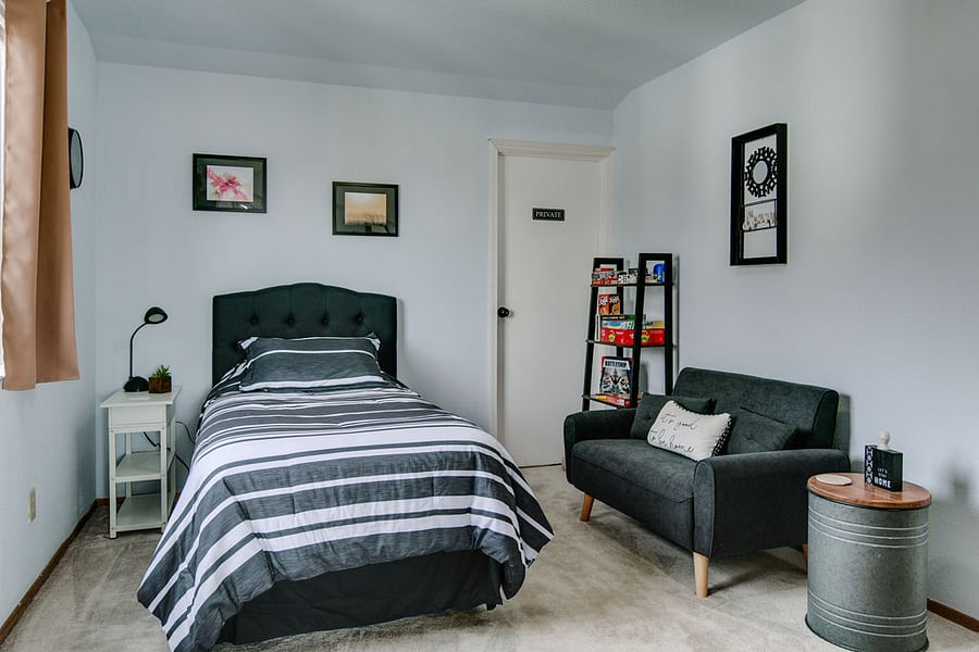 2nd bedroom with twin bed, small couch and shelves with games