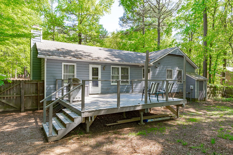 Large back deck complete with outdoor furniture, propane grill, and a view of the fenced in backyard.