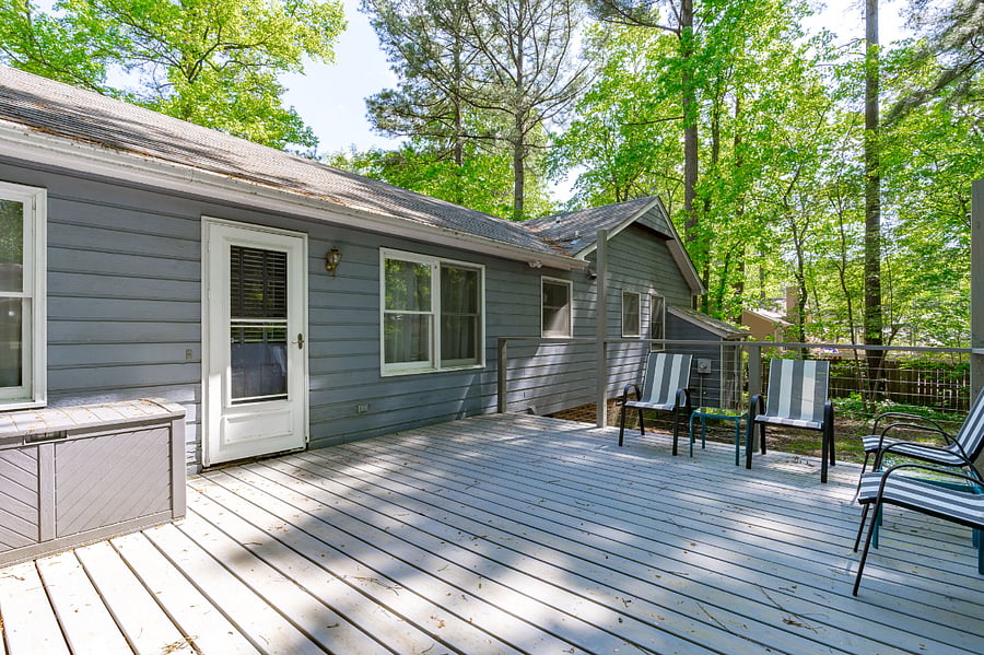 Large back deck complete with outdoor furniture, propane grill, and a view of the fenced in backyard.