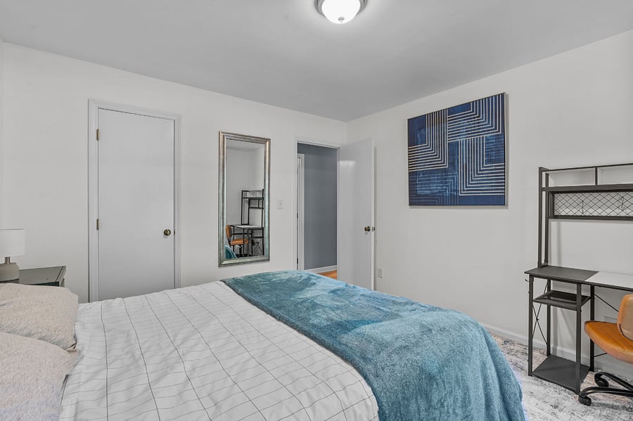 First guest room with a queen size bed, desk, and walk in closet