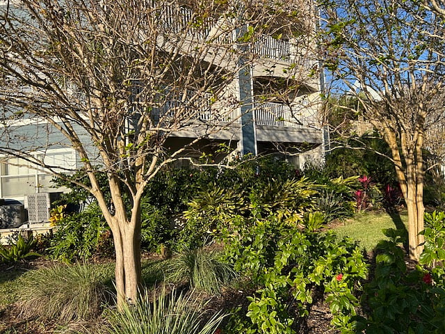 Exterior of building with tropical plantings. Unit is bottom left.