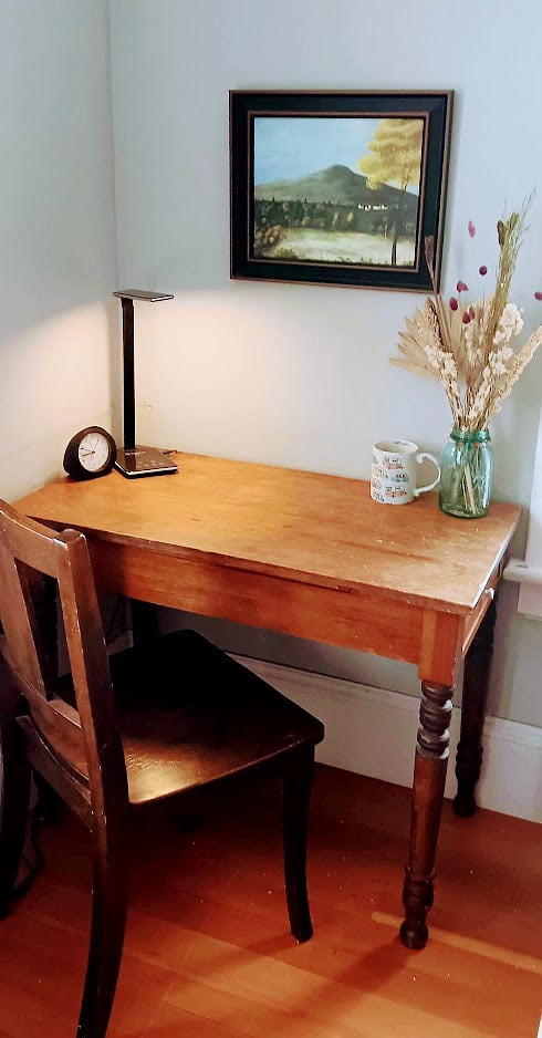 Desk (in living room) with clock, light, for laptop.