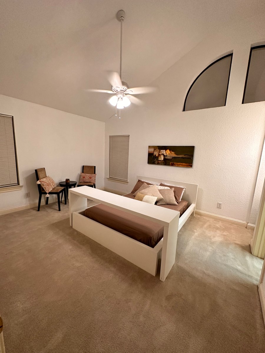 Bed has a desk or table that slips over bed to allow for reading eating working, Etc