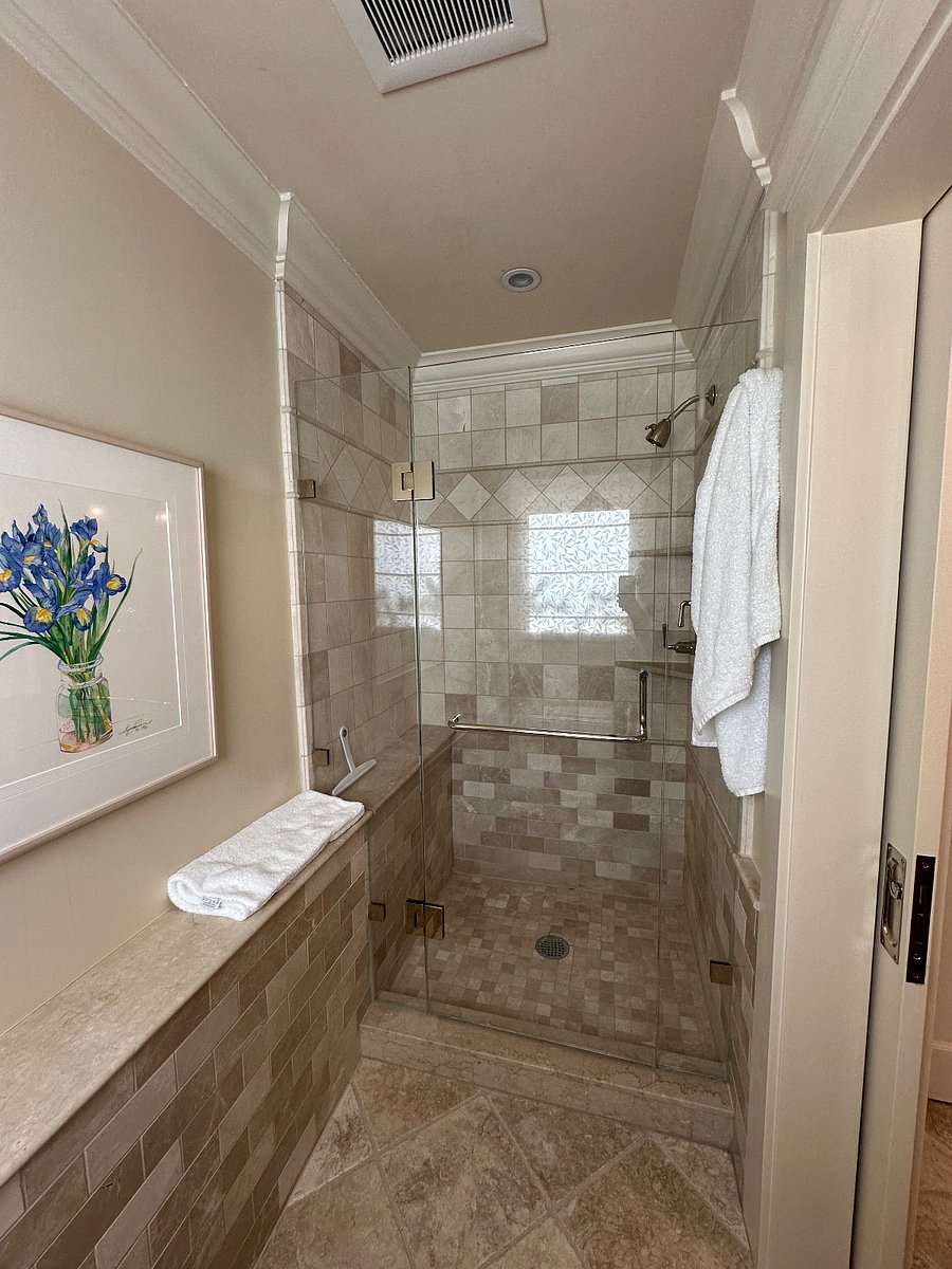 Travertine stone shower with clear glass door.
