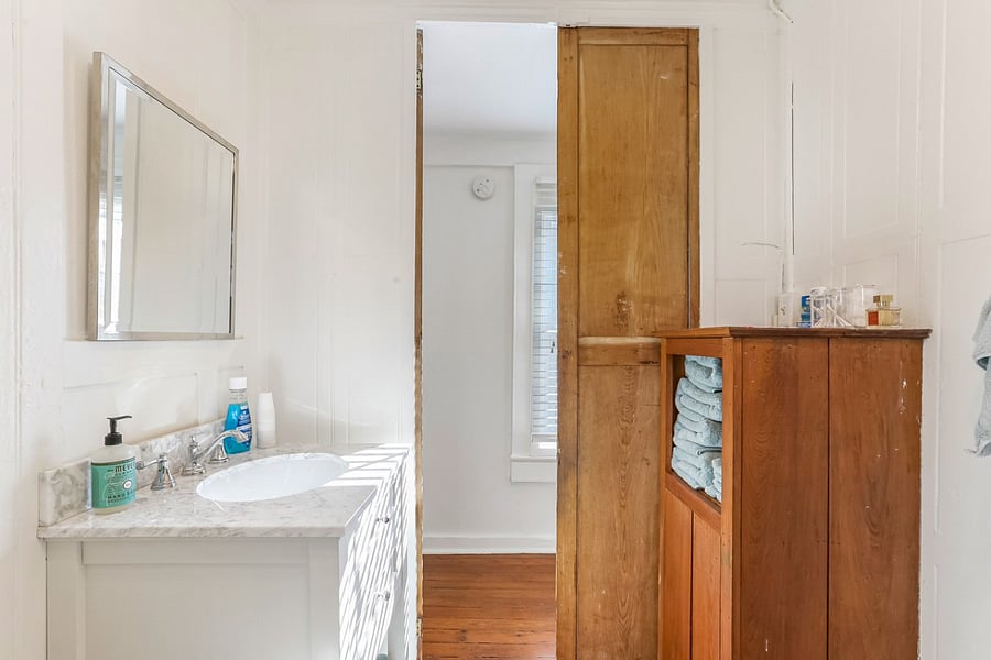 Bathroom sink and marble vanity with mirror. Built-in wooden cabinet with abundant plush towels