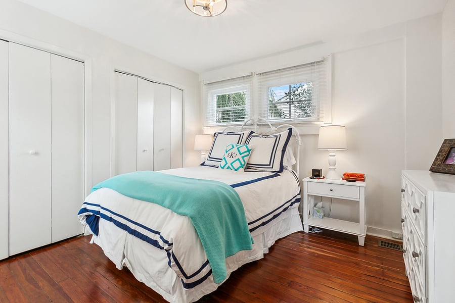 Another view of the bedroom highlighting the ample closet space and showing the bed, dresser, nightstands, and lamps