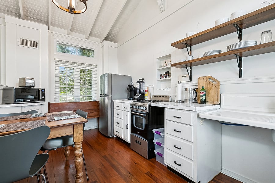 The kitchen includes a blender for smoothies, protein shakes, and frozen drinks. Open shelving, full-size appliances, and a dining table complete the space.