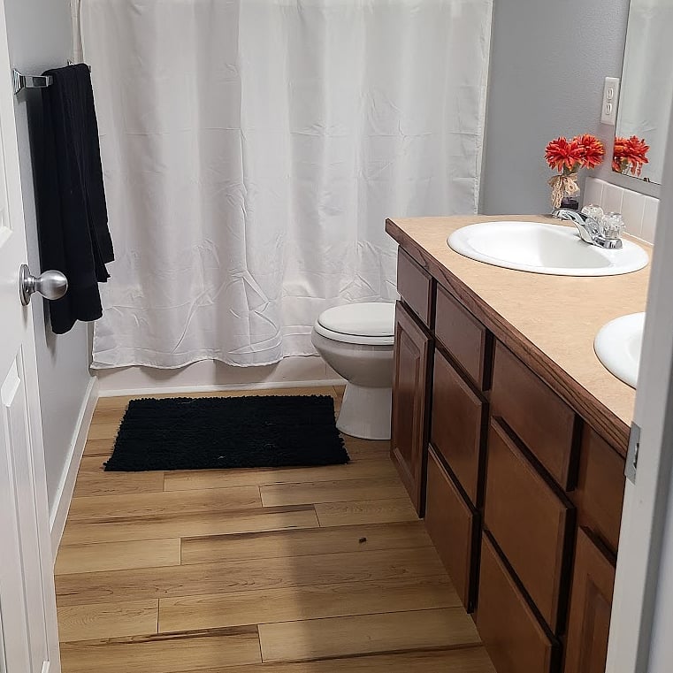Shared tenant bathroom with separate sinks and cupboard storage.