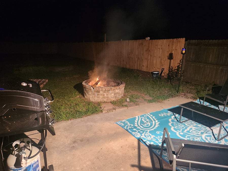 Outdoor area in back yard has a large fenced yard with a fire pit, seating for 4 and a grill with all needed grill tools.