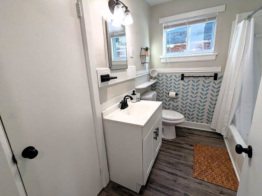The large bathroom has modern fixtures, and the accessories and custom wall paintings elevate the space. Tons of storage is available for you in the closet in here.
