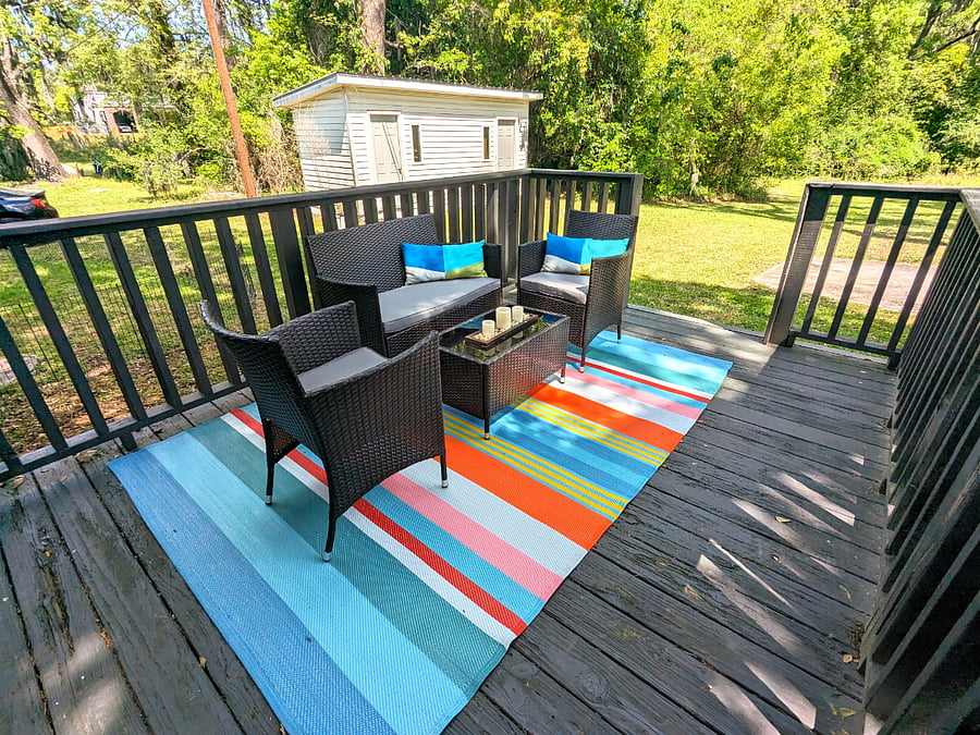 The back deck has a conversation set from which to enjoy the spacious, shady back yard.