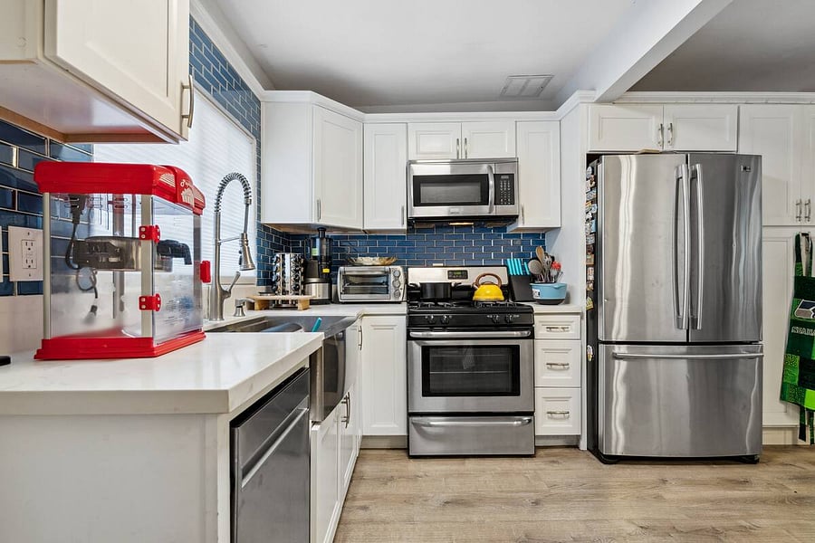 Cook, chill, and snack in style, this fully equipped kitchen features stainless steel appliances, bold blue backsplash, and a fun popcorn machine for movie nights.
