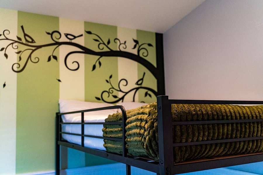 A whimsical touch guests love, fall asleep under a charming tree mural in this fun and restful bunk space.
