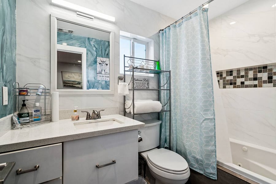 Relax and refresh in this spotless bathroom featuring modern fixtures, extra towels, and calming blue accents for a spa-like feel.