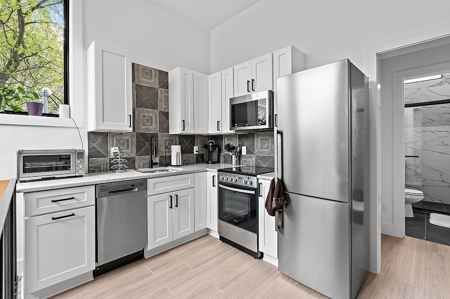 Fully stocked Kitchen with all amenities and lots of natural light. The trash can is hidden in the far-left drawers.