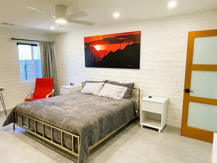 Bedroom with King Bed. Large hanging cedar closet.  Sitting area has chair next to exterior window. Window has blackout blinds, blackout curtains and shears.